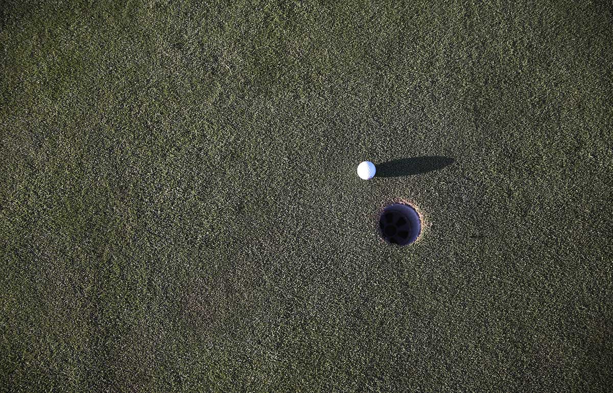 Balle de golf près d'un trou
