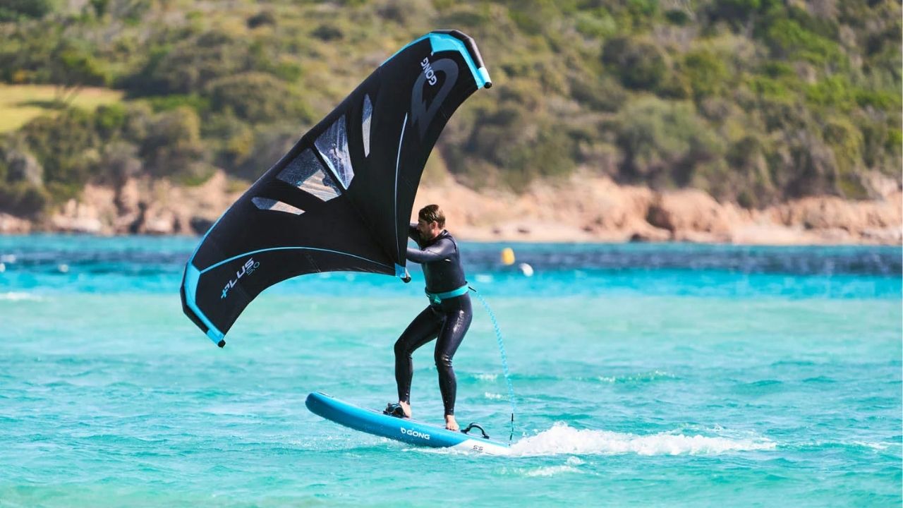 Rider en wing foil sur la mer au lever du soleil, symbole de la glisse moderne en 2026.